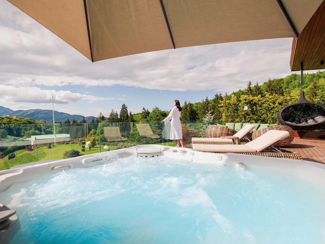 Bubbling hot tub and a woman in a robe on an Eden Hill terrace overlooking the green valley.