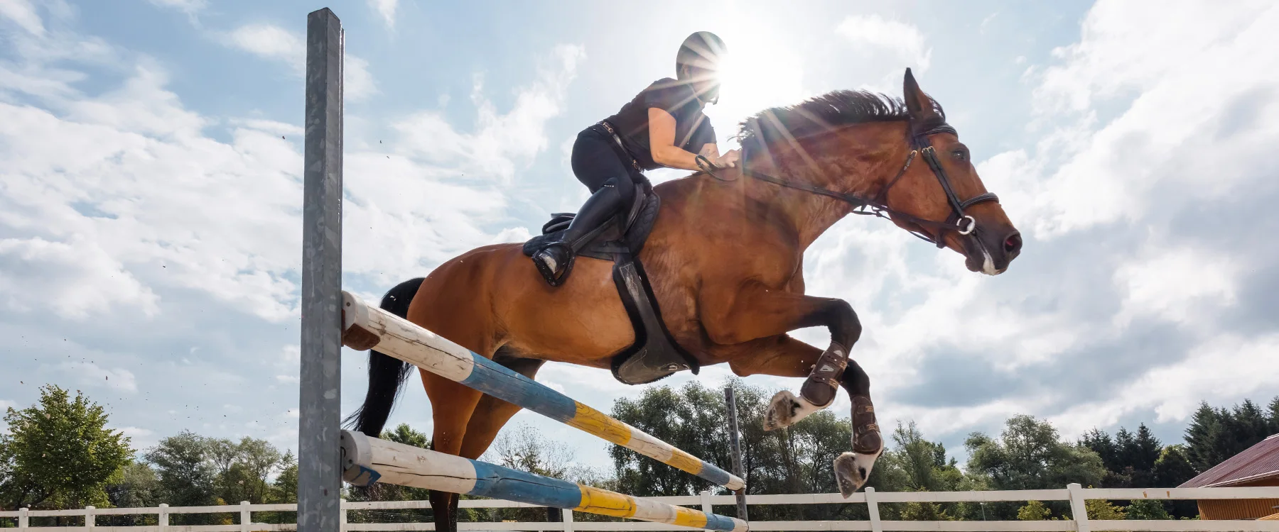 Horse and rider jumping a striped obstacle at an equestrian competition.