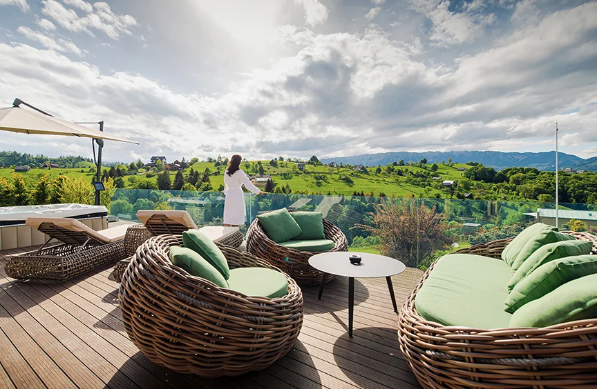 Round wicker seats and a woman in a robe on an Eden Hill terrace overlooking the valley.