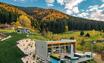 Aerial view of a glass-fronted Eden Hill villa among autumn trees and curving paths.