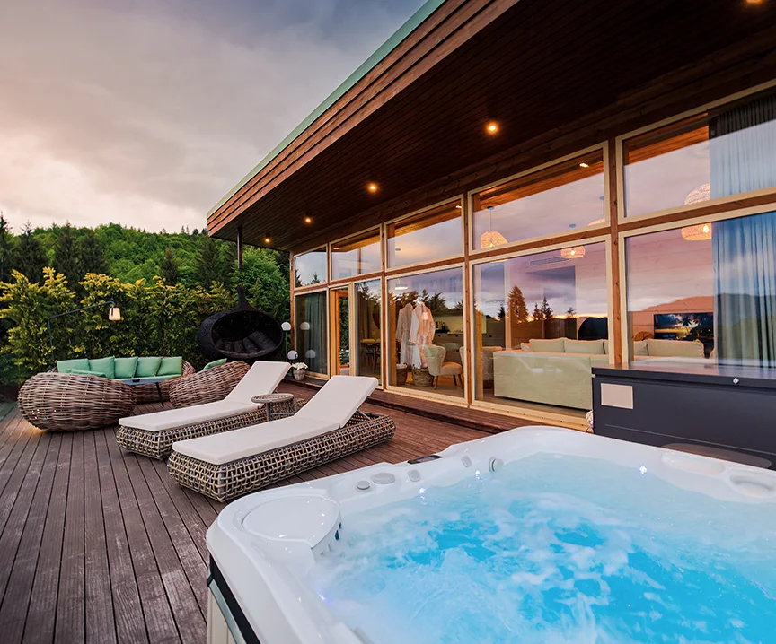 Illuminated hot tub and loungers on an Eden Hill villa terrace at sunset.