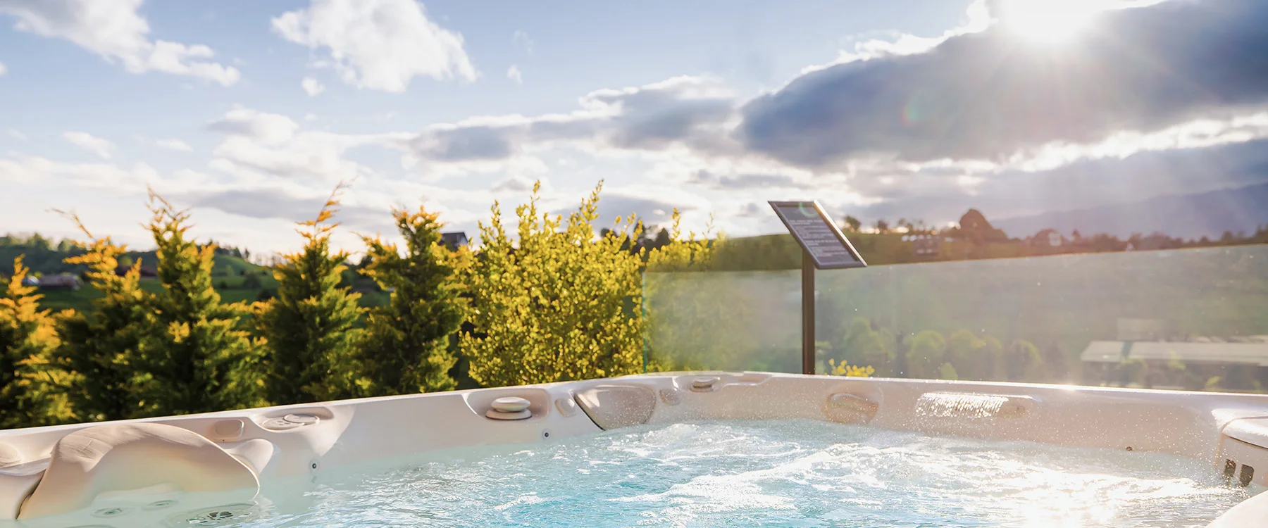 Bubbling hot tub on an Eden Hill terrace beside a glass railing in the sunset light.