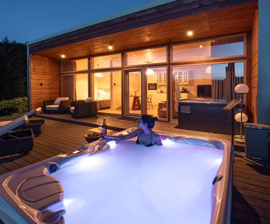 Woman in an illuminated hot tub outside an Eden Hill villa with glowing windows at dusk.
