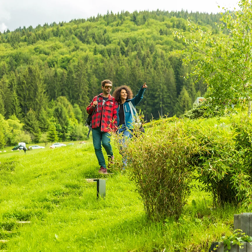 Couple walking through the Eden Hill garden along a grassy path bordered by shrubs.